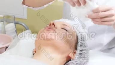 美容师在客户的下巴`擦奶油，做美容手术清洁面部美容